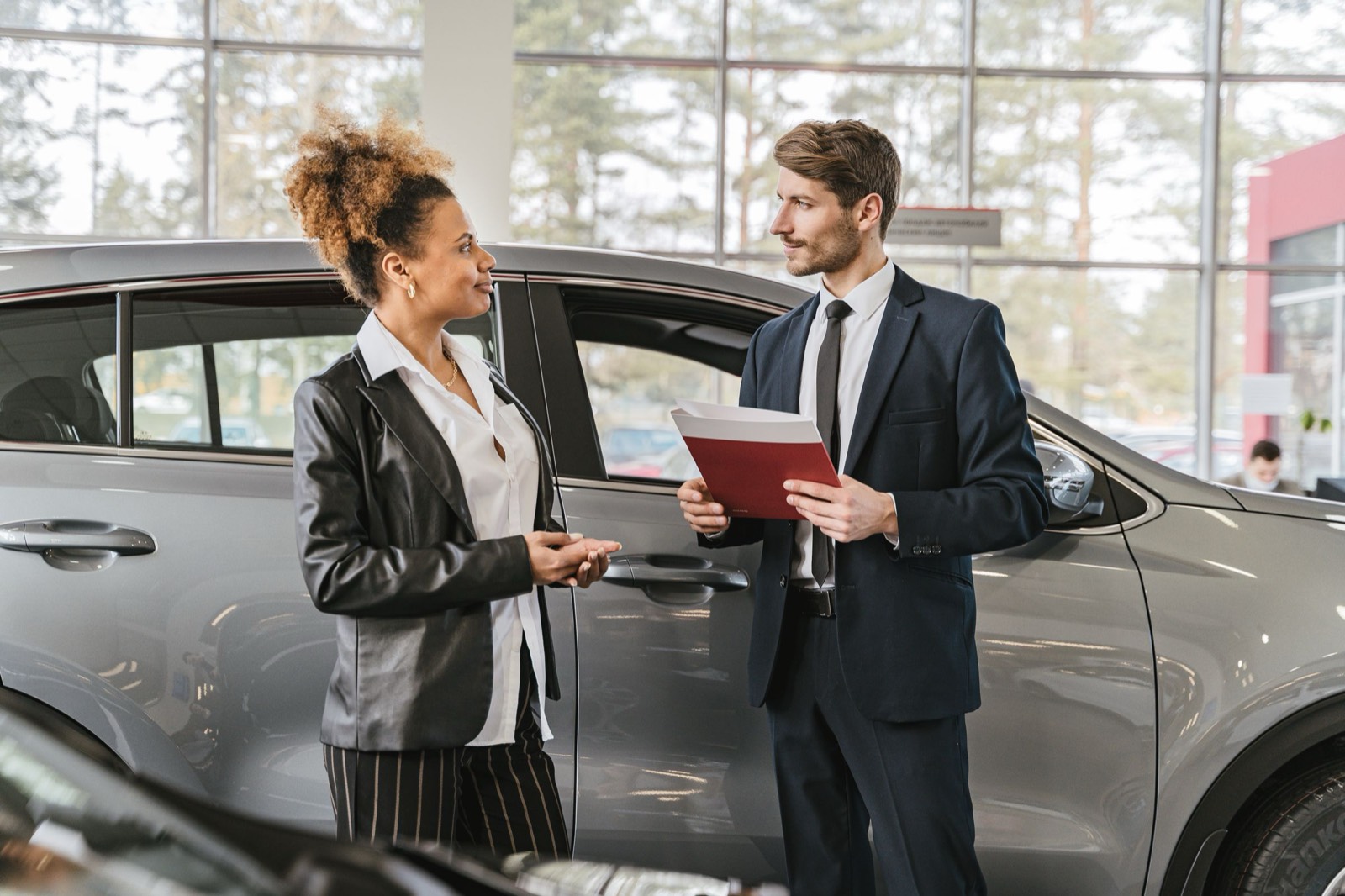 A car salesman going over paperwork with a customer in the showroom