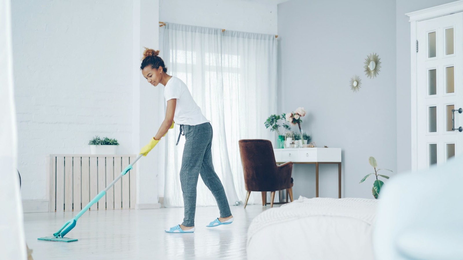 A cleaner mopping a bright living room