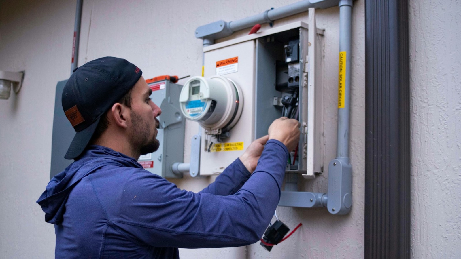 An electrician working on an electrical panel