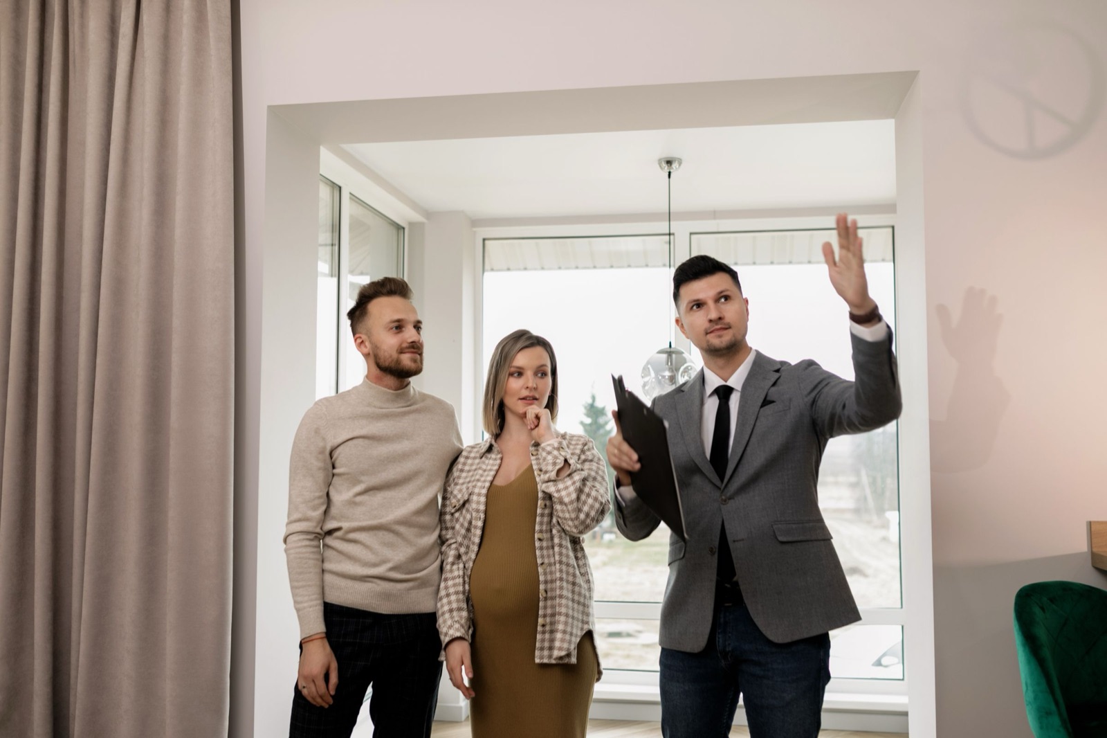 A real estate agent showing a bright home to a young couple