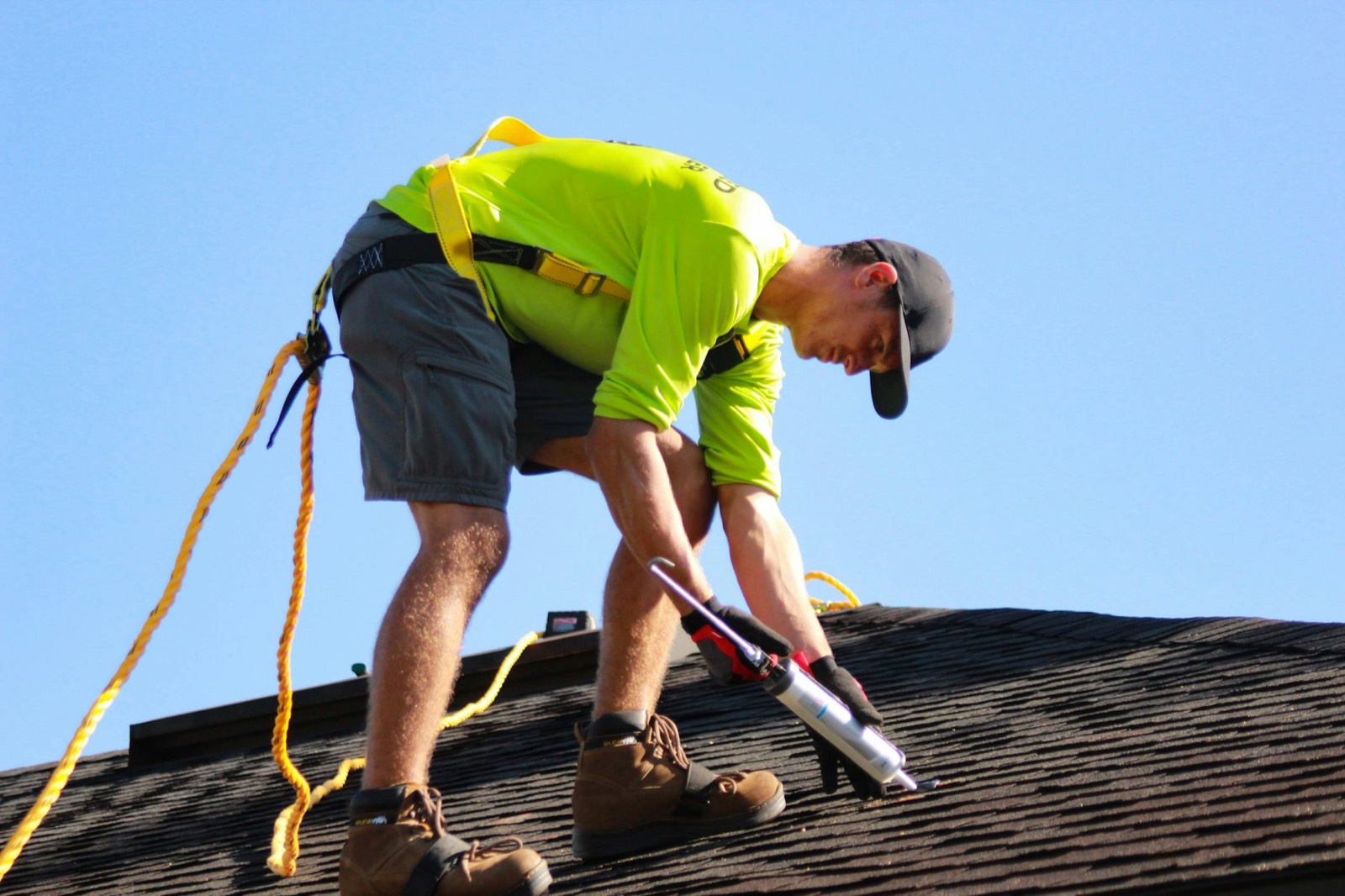 A roofer sealing shingles on a roof
